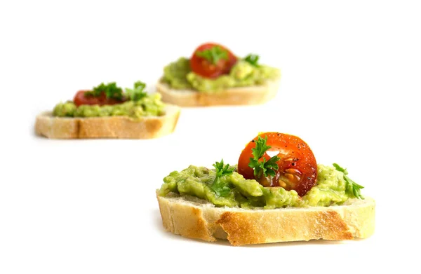 Kanapéer med avokado kräm eller guacamole och tomater isolerad på vit — Stockfoto