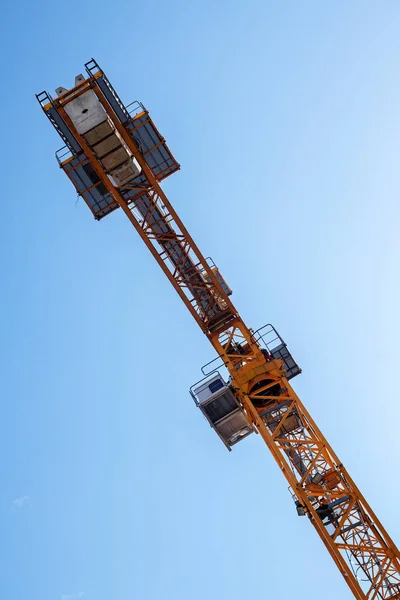 Détail de la grue contre un ciel bleu, construction métallique orange et poids en béton — Photo