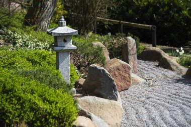 Herdem yeşil bitkiler, kaya ve komisyonlu çakıl, zen Bahçe peyzaj tasarımı arasında taş fener