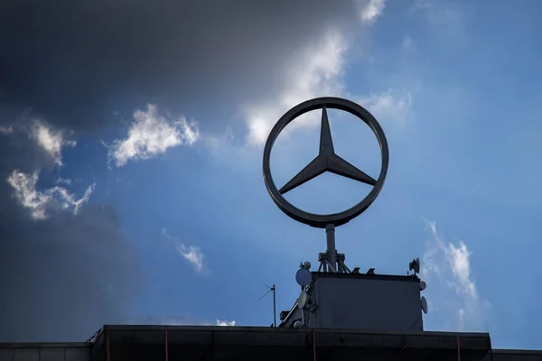 Sarbruecken, Germany, 23 March 2017: Mercedes star, the logo sign of the brand Mercedes Benz against a blue sky with dark cloud — Stock Photo, Image