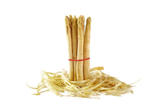 Bunch of white asparagus standing in asparagus peel, isolated on white — Stock Photo, Image