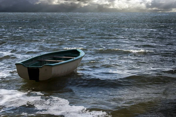 Barca a remi vuota galleggia solitario sulle onde del mare alle nuvole al largo orizzonte, paesaggio marino con spazio copia — Foto Stock