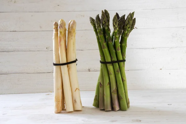 Asperges, een groene en een witte bos staan op een wit geverfde houten achtergrond, kopiëren ruimte — Stockfoto