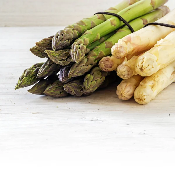 Asparagus, green and white bunch on bright painted wood, background with copy space fades to white — Stock Photo, Image