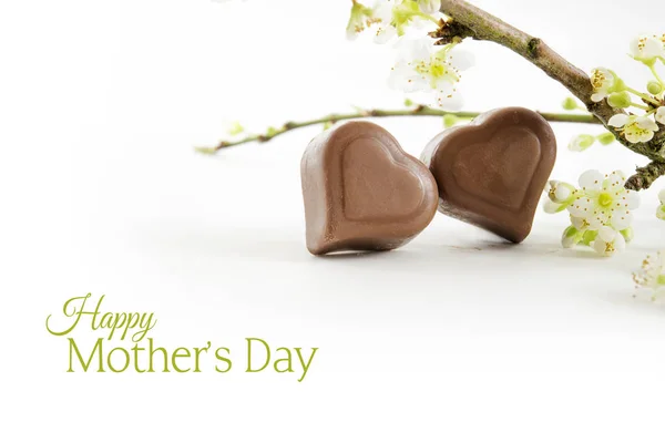 Dos corazones de chocolate y ramas florecientes aisladas con sombra sobre un fondo blanco, texto de muestra Feliz Día de la Madre —  Fotos de Stock