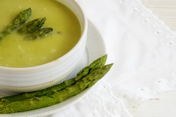 Green asparagus soup in a bowl on a white tablecloth, copy space — Stock Photo, Image