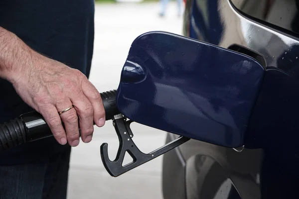 La mano del hombre sostiene una pistola de combustible y repostar su coche con gasolina o diesel en la gasolinera —  Fotos de Stock