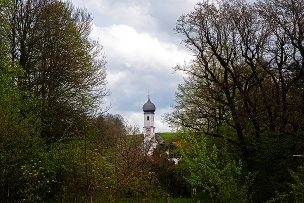 Clocher typique de l'église catholique bavaroise avec dôme d'oignon entre les arbres verts et les buissons comme dans un nid, bavière près des Alpes — Photo