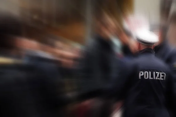 Deutscher Polizist im Einsatz, von hinten erschossen, Fokus auf Jacke mit Polizei-Schriftzug, d.h. Polizei, verschwommener Hintergrund mit Zoomeffekt — Stockfoto