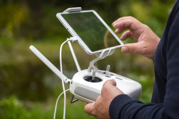 Beheren van een externe helikopter of quadrocopter met mobiele telefoon / tablet bekijken tegen de achtergrond van een groene natuur — Stockfoto