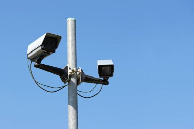 İki cctv güvenlik kameraları açık mavi gökyüzü karşı caddede pilon üzerinde