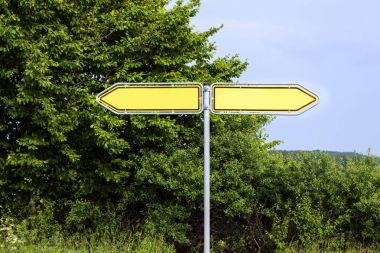 Yeşil çalılar ve mavi gökyüzü karşı ters yönde işaret boş sarı yol işaretleri