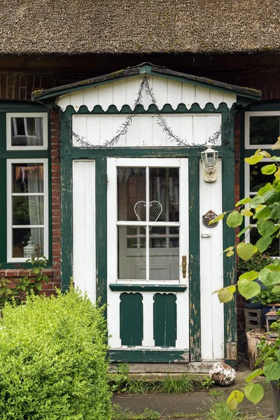 Hermosa puerta de entrada de madera vieja en verde y blanco en una típica casa de techo de paja tradicional en el norte de Alemania , — Foto de Stock