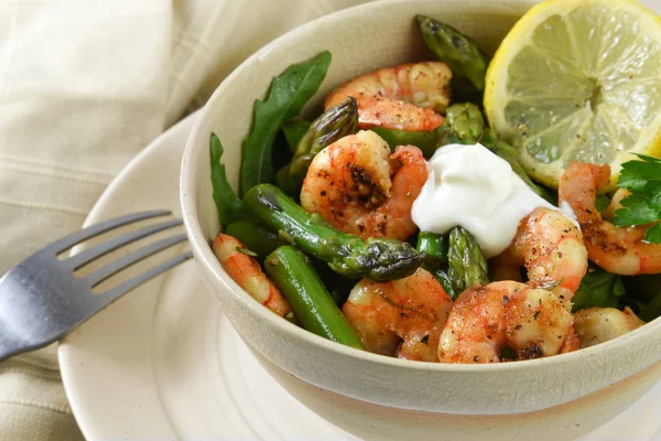 Ensalada de camarones de gambas, espárragos verdes, rúcula y rodaja de limón en un tazón en un plato — Foto de Stock