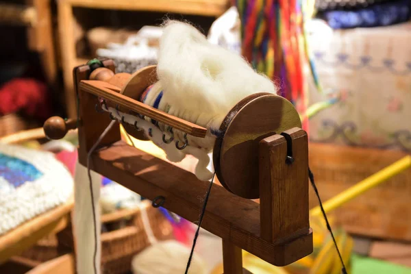 チラシと屋外のクラフト市場での手紡ぎの天然ウールと木製糸車のボビン — ストック写真