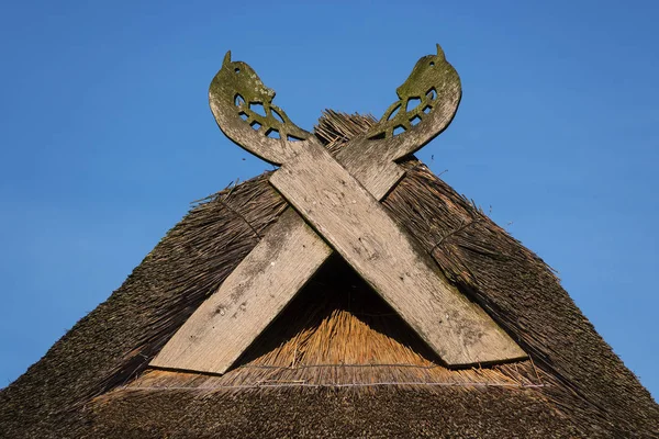 Gavelförsedda brädor i form av hästhuvud på halmtak mot en blå himmel på en solig dag, typisk för traditionella hus i norra Tyskland — Stockfoto