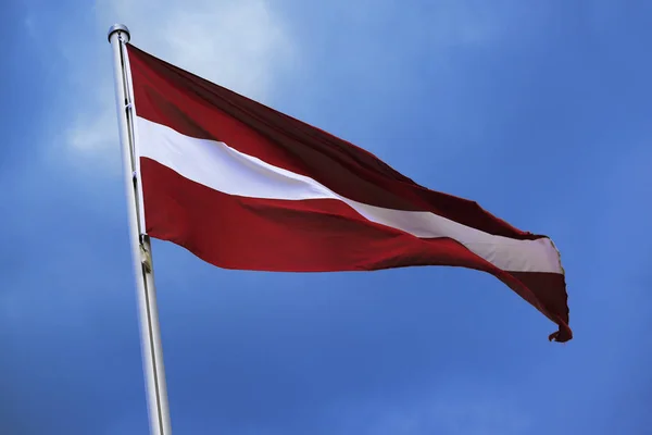 Ausztria, zászlaja piros, fehér, piros, csíkos nemzeti szimbólum vagy jel az európai ország, csapkodott a szélben a kék ég, a felhők ellen egy napsütéses napon — Stock Fotó