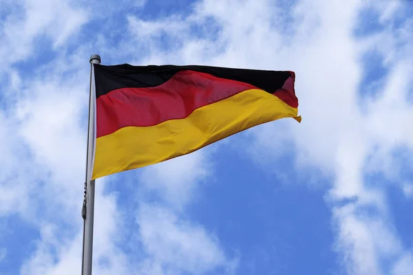 Bandera de Alemania con rayas en rojo, negro y oro, símbolo nacional o signo del país europeo, contra el cielo azul con nubes — Foto de Stock