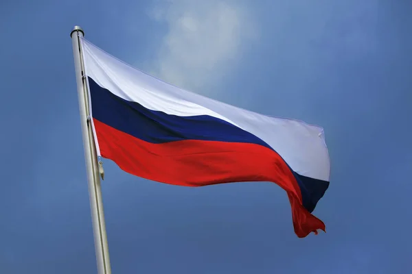 Az Oroszország zászlaja sávok fehér, kék és piros, nemzeti szimbólum vagy jele az országban, csapkodott a szélben, szemben a kék ég, a felhők — Stock Fotó