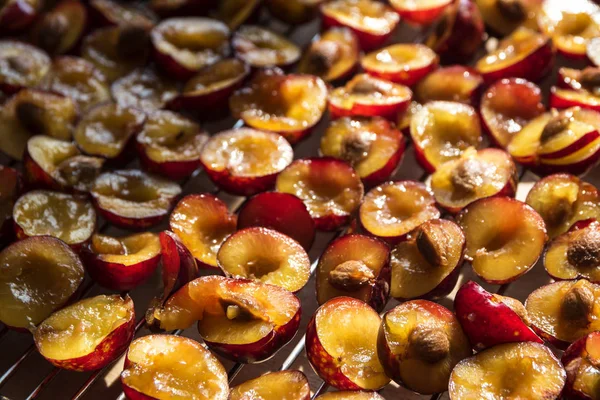 Sliced red plums for the cake on a grating, food or baking background — Stock Photo, Image