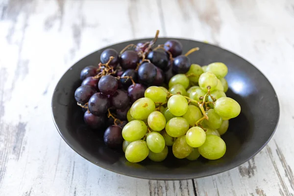 Świeży zielony i fioletowy winogron w misce na biały drewno malowane — Zdjęcie stockowe
