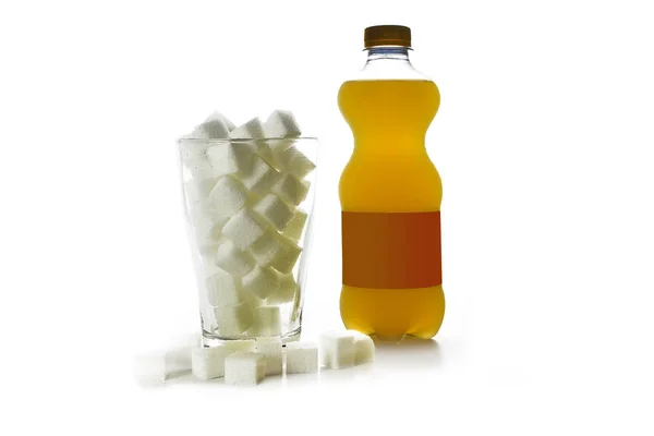 Пляшка апельсинового солодкого напою і склянка, наповнена цукровими кубиками, концепція нездорових напоїв, ізольовані на білому тлі — стокове фото