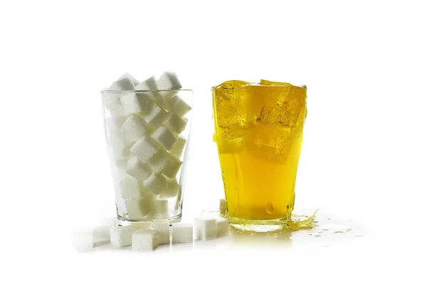 Vaso lleno de terrones de azúcar en comparación con un vaso con una bebida dulce amarilla, aislado sobre un fondo blanco — Foto de Stock