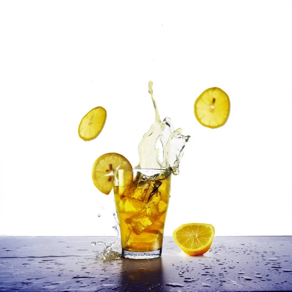 Bebida amarela com salpicos, cubos de gelo e fatias de limões voadores, bebida refrescante de suco, refrigerante ou chá gelado isolado — Fotografia de Stock