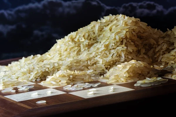 Шахматная доска с растущими кучами рисовых зерен, легенда об экспоненциальной функции и пределе роста, темное небо — стоковое фото