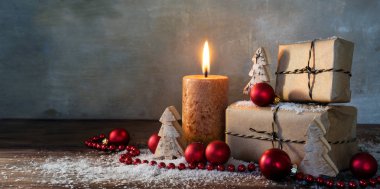 iki hediye kutuları ve yanan bir muma kırmızı Noel baubles küçük ahşap oyuncak ağaçlarda bazı kar rustik ahşap üzerine, antika arka plan büyük kopya alanı, panorama biçimi ile dekore edilmiş ve