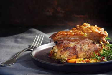 Sulu kızarmış domuz eti gevrek kabuk, biberiye ve sebze rustik koyu arka plan, moody ışık, gri peçeteye kopyalama alanı