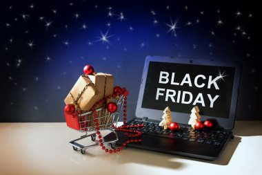 siyah Cuma online alışveriş, Noel baubles ve hediye kutuları dışında metin, karanlık yıldız gökyüzü arka plan, kopya alanı ile bir dizüstü bilgisayar sürüş bir alışveriş arabası