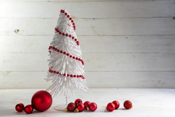 Kleiner weißer Draht-Weihnachtsbaum mit roten Kugeln und Kugeln vor rustikalem grauen Holzhintergrund mit großem Kopierraum — Stockfoto