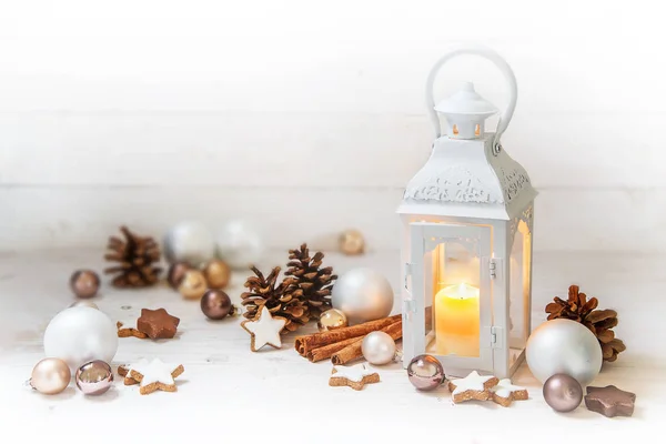Linterna de Navidad con luz de vela encendida y decoración como bolas, conos de pino y galletas estrella de canela en madera blanca rústica con espacio para copiar —  Fotos de Stock