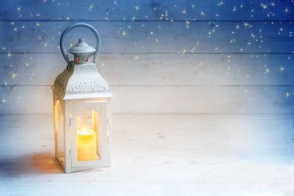 Weihnachtshintergrund mit Laterne und brennender Kerze auf rustikalem weißem Holz, blauer Himmel mit Sternen, Kopierraum — Stockfoto