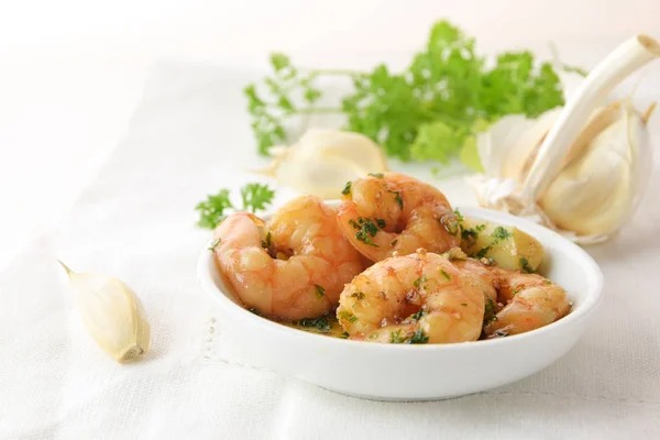 Shrimps with garlic, olive oil and parsley in sherry sauce in a white bowl, spanish tapas appetizer gambas al ajillo, white napkin and herb garnish in the background, copy space — Stock Photo, Image