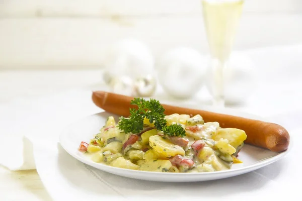 Ensalada de patatas con salchicha salchicha y guarnición de perejil en una mesa de madera blanca, cena típica de Navidad alemana, espacio para copiar — Foto de Stock