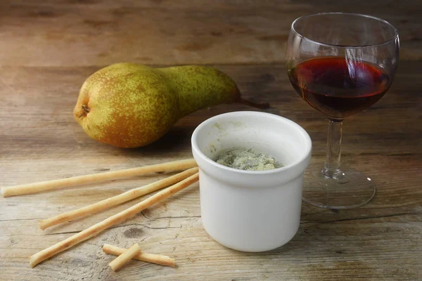 Potted blue stilton cheese in a ceramic jar, port wine, pear and some nibble sticks on a rustic wooden table, copy space — Stock Photo, Image