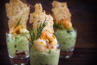 meze parti aperatifler gözlük, avokado krem guacamole kaplan karides karides ve gevrek peynir kraker üzerinde koyu renkli rustik ahşap, yakın çekim