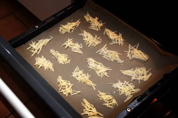 Membuat keripik parmesan, keju parut dalam timbunan di atas baking siap untuk dipanggang dalam oven — Stok Foto