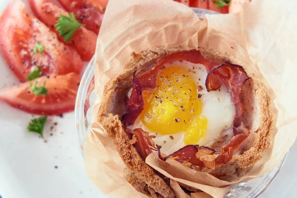 Śniadanie muffin z jajka i boczek w tosty dekorować chleba, pomidor i pietruszka w tle, z bliska z góry — Zdjęcie stockowe