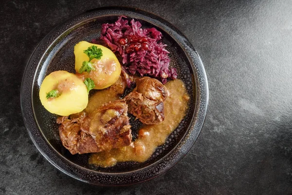 Beef rolls, traditional german meal, filled meat rouladen with red cabbage, potatoes and sauce on a dark plate, dgray slate stone background with copy space — Stok Foto