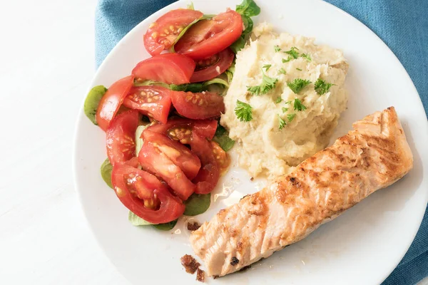 Grillad laxfilé med palsternacka puré, tomatsallad och persilja Garnera, hälsosam kost måltid på en vit platta och blå servett, hög vinkel vy ovanifrån, kopia utrymme — Stockfoto