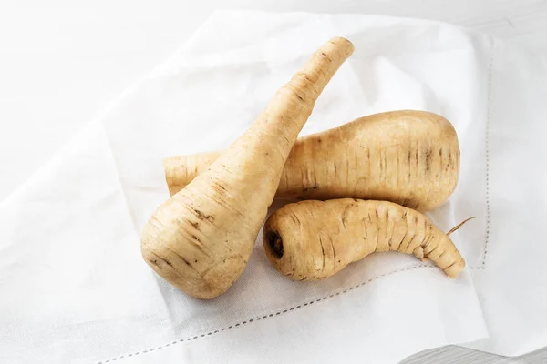 Pastinaak, rauwe wortelgroenten op een witte keuken handdoek, kopie ruimte — Stockfoto