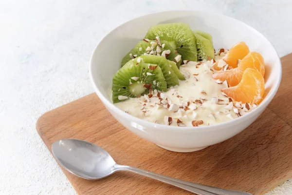 Café da manhã saudável com proteína de quark ou queijo coalhado, óleo de linhaça com ácidos graxos ômega 3, frutas e nozes frescas, dieta budwig em uma tigela branca em uma placa de cozinha de madeira e um fundo leve com espaço de cópia — Fotografia de Stock