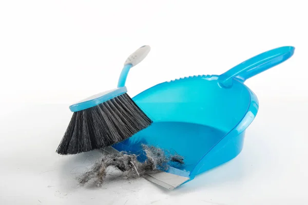 Spring cleaning concept, blue hand brush and dustpan sweeping dust bunnies, copy space, light gray background fading to white — Stock Photo, Image