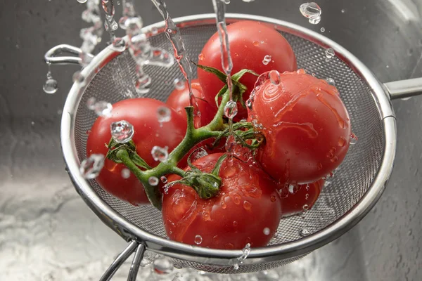 Pomodori freschi in un cullender di metallo tra molte gocce d'acqua, lavando e preparando cibi sani — Foto Stock