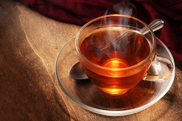 Black tea freshly brewed in a glass cup, steaming hot drink on dark rustic wood, copy space — Stock Photo, Image