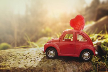 Rieps, Almanya - 1 Şubat 2018: küçük kırmızı eski model araba kayalık bir günbatımı manzara, kopya alanı içinde Sevgililer ya da anneler günü için bir kalp taşır