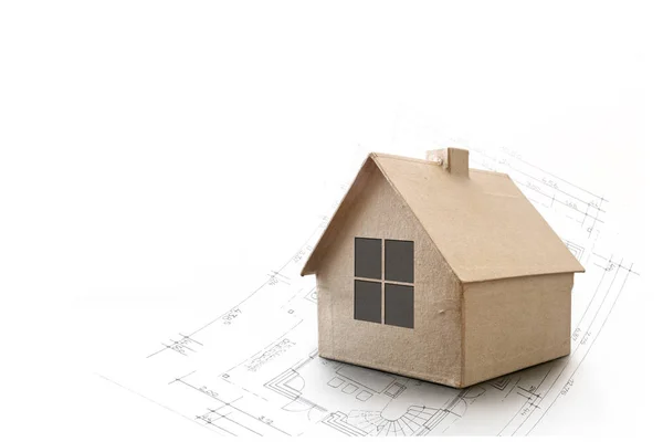 Modelo casa feita de papelão em um plano de arquitetura, fundo canto isolado em branco, conceito imobiliário, espaço de cópia — Fotografia de Stock